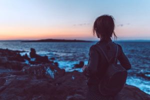 Woman looking out into ocean at sunset