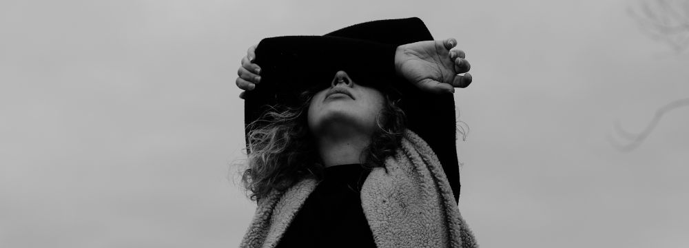 woman covering her eyes with both arms crossed in black and white