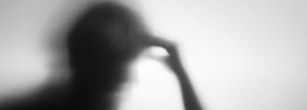 Blurry shadow of person holding head with one hand