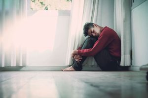 man sitting barefoot on floor with eyes closed